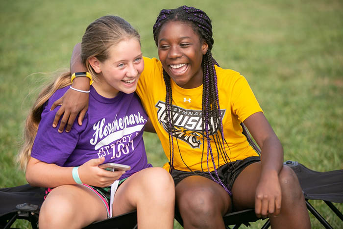 african american girl and caucasian girl giving each other a side hug.