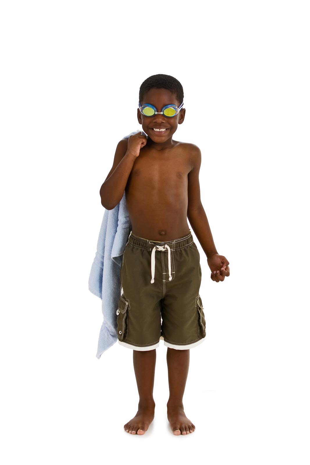 A young African American boy wearing swim trunks and goggles and carrying a towel. Isolated on a white background.