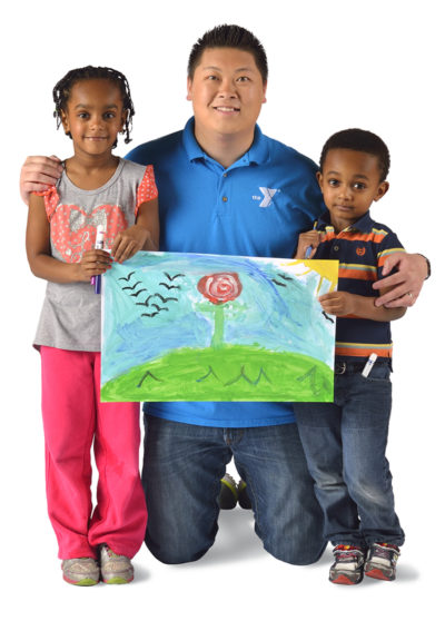 YMCA child care worker with two children holding artwork