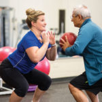 personal trainer working out with an active older adult